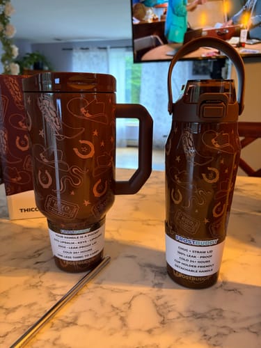 Customer's two brown Thicc Buddy mugs with western patterns sitting on a marble countertop with a silver straw.