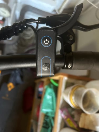 Customer's Ausom electric scooter throttle mounted on handlebars, featuring a circular power button and settings icon.