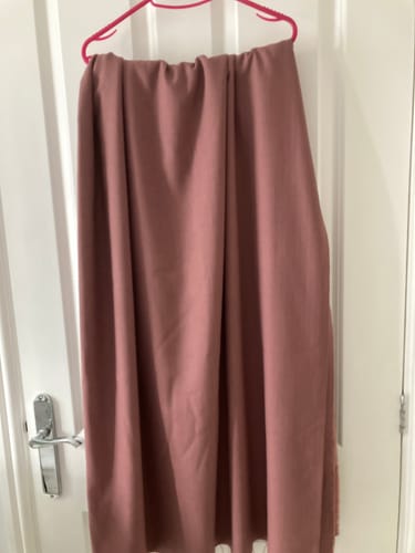 Customer's draped dusty-pink Bamboo Linen Blend fabric hanging on a hanger against a door.