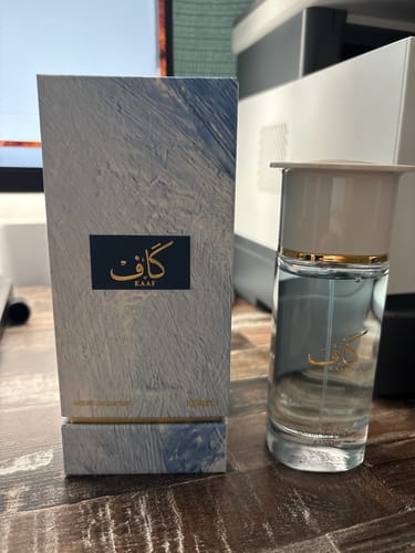 Reviewer's Perfume Ahmed al Maghribi KAAF bottle and textured blue packaging on a wooden surface.