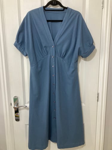 Customer's denim blue dress made from Bamboo Linen Blend Fabric hanging on a door.