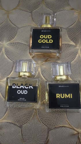 Customer's Royal Oud Collection featuring three clear glass perfume bottles with black labels on a textured gold surface.