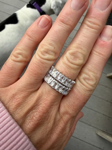 Reviewer's hand wearing two silver eternity rings with clear stones