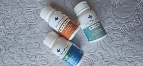 Customer's Reset Bundle bottles of Ashwagandha, Sea Moss, and Moringa on a textured white fabric surface.