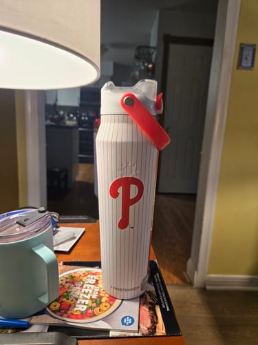 Customer's white Philadelphia Phillies Bottle Buddy standing on a table next to a mug.