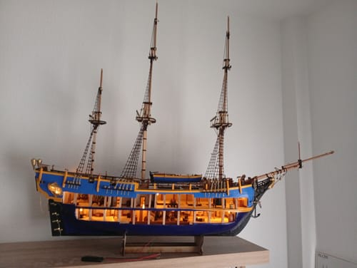 Customer's HMS Bounty ship model with glowing interior lights displayed on a wooden surface.