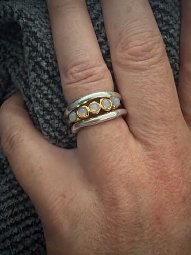 Customer's Golden Moonstone Eternity Ring stacked with silver bands on a finger.