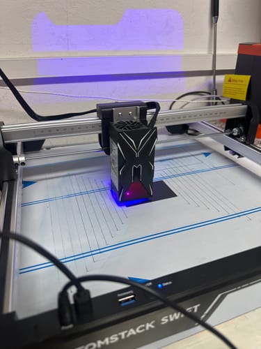 Customer's AtomStack Swift laser engraver operating with a visible blue light beam on the workspace.