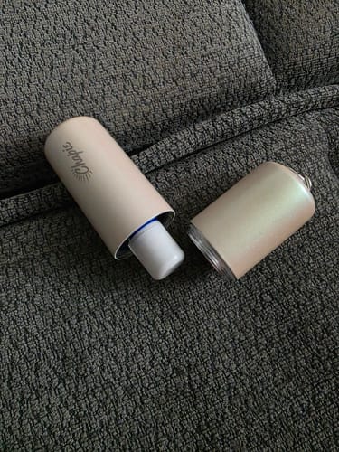 Reviewer's open Chapie Plus metal container with a lip balm tube, sitting on a textured couch.