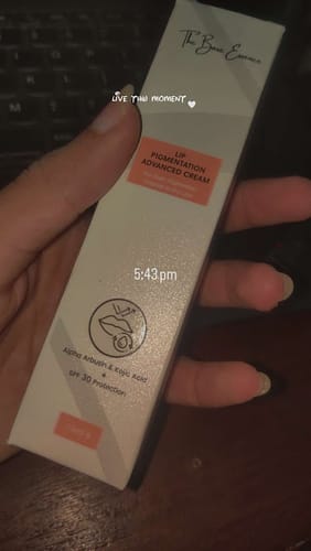 Customer's hand holding the rectangular, beige box of Advance Lip Pigmentation Cream.