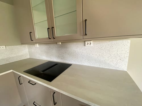 Customer's Lisboa Terrazzo hvit selvklebende fliser installert som en lys kjøkken-backsplash bak kokeplaten.