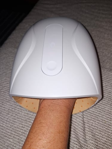 Customer's hand inserted into the white, dome-shaped HandCare+ Regeneráló Kézmasszírozó for a therapy session.