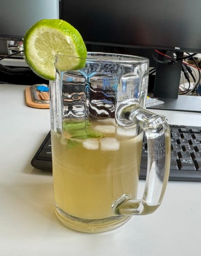 Customer's Wasserkefir in a glass mug with ice and a lime slice on a desk with a computer keyboard.