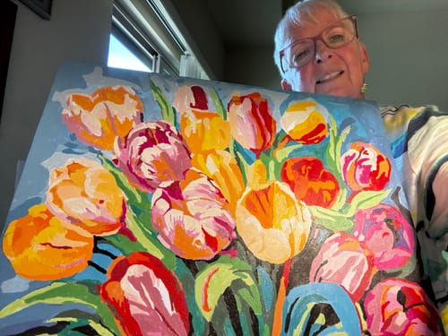 Customer's completed colorful flower canvas painting from the Number Remover Marker set held by a smiling person.