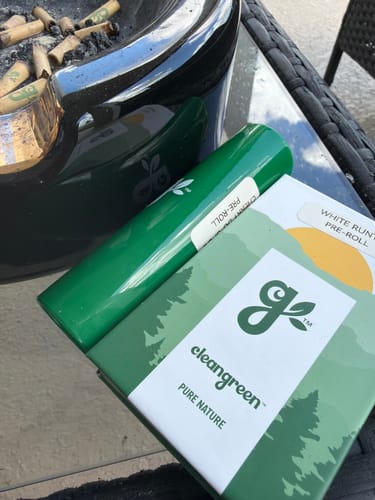 Customer's White Runtz Pre-Roll green packaging sitting on a glass table next to an ashtray.