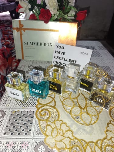 Customer's Summer Box containing multiple fragrance bottles, a note, and floral decorations on a patterned table.