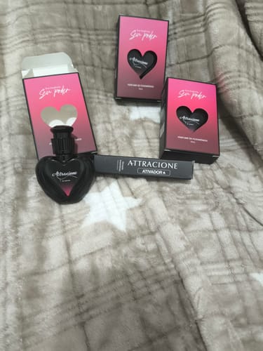 Customer's Ativador de Feromônios Attracione with its heart-shaped bottle and boxes on a soft patterned blanket.