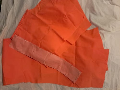 Customer's bright coral polycotton fabric cut into pieces for a sewing project on a white surface