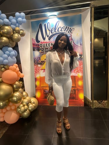 Customer's Smooth Sculpt Waist Capri Leggings worn with a white top standing in front of a welcome sign.