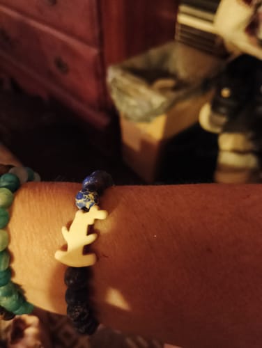 Customer's wrist wearing the Shark Week Bracelet with a white hammerhead charm and dark beads.
