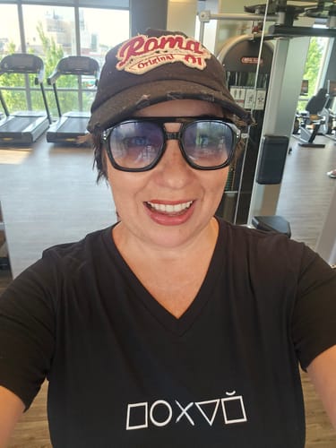 Reviewer wearing a black Pohuy Women’s relaxed v-neck Tee in a gym setting, close-up view.