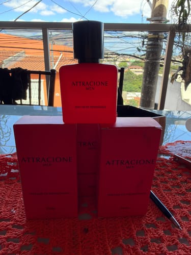 Customer's Attracione Men perfume bottle and two red packaging boxes displayed on a red lace tablecloth.