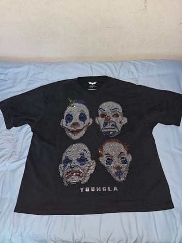 Customer's Batman Rhinestone Tee on a light blue fabric surface, showing four joker clown character portraits.