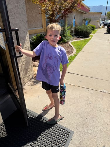 Customer's child holding a patterned Bottle Buddy while standing in a doorway.