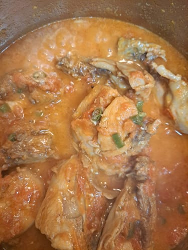 Customer's Halal Omega-3 Whole Chicken pieces cooking in a red, tomato-based sauce inside a pot.