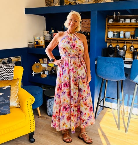 Reviewer wearing a floral halter neck dress made from Garden Delight linen viscose fabric in an interior setting.
