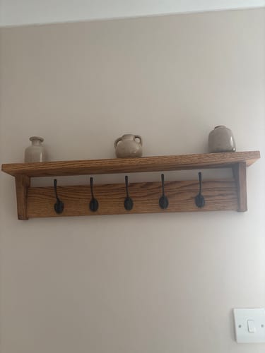 Customer's Solid Oak Coat Rack with shelf mounted on a wall, decorated with three small neutral vases.