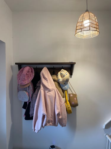 Customer's Solid Oak Coat Rack with storage shelf installed on a white wall, filled with coats, bags, and hats.