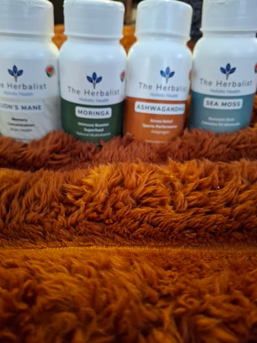 Customer's Lion's Mane and other The Herbalist supplements sitting on a shaggy orange surface.