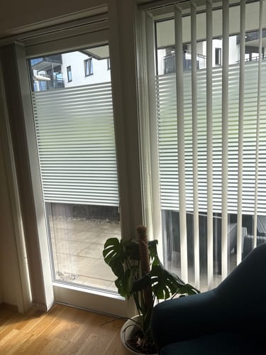 Kundens Static Linia vindusfolie med hvite striper montert på vindusdører med utsikt til en hage.