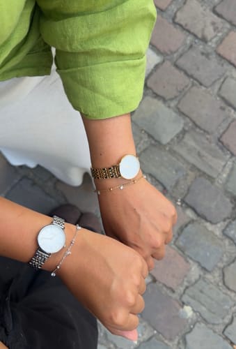 Customer's wrists showing a gold and a silver Alaia Bracelet, each paired with a watch.