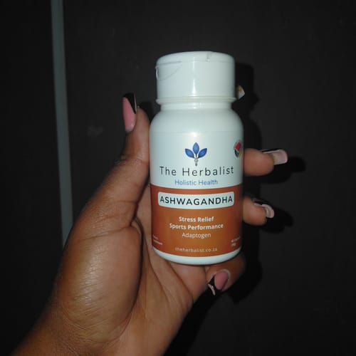 Customer's hand holding a white bottle of The Herbalist Ashwagandha capsules.