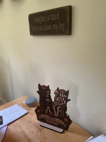 Customer's Till Death Do Us Part Skeleton Couple wooden plaque displayed on a wooden table in a living room.