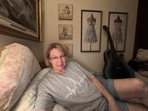 Reviewer wearing a grey Guitar Heartbeat T-Shirt while lounging at home next to a guitar.