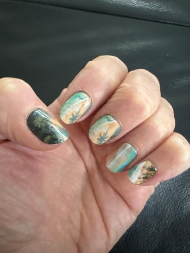 Reviewer's hand showing Summer Haven UV Gel Nail Wraps with a detailed beach scene and palm trees on the nails.