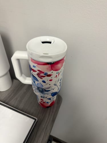 Reviewer's floral Thicc Buddy 40oz tumbler with a white lid sitting on a dark wooden surface.