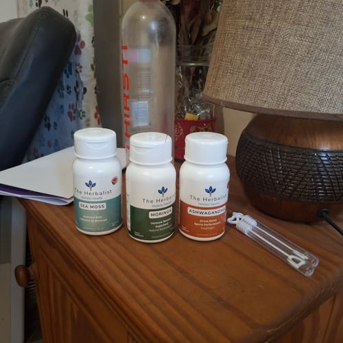 Customer's Reset Bundle, including Sea Moss, Moringa, and Ashwagandha bottles, sitting on a wooden nightstand.