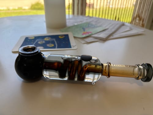 Reviewer's freeze pipe containing Roll Ready Ground flower, resting on a table.