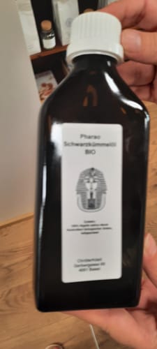 Kundenfoto des Schwarzkümmelöl Bio in einer dunklen Flasche mit weißem Verschluss, von einer Hand gehalten.