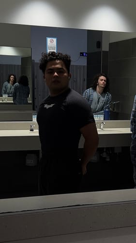 Reviewer's black Batman Compression Tee, shown from the side in a bathroom mirror.