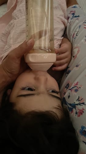 Customer's Hegen baby bottle being used by a baby for feeding while lying down.