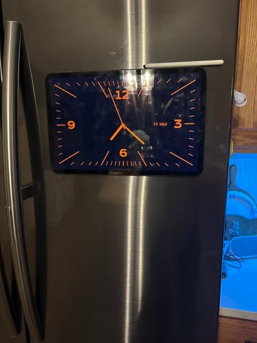 Customer's mounted FridgeCal calendar on a stainless steel refrigerator with a bright digital clock display.