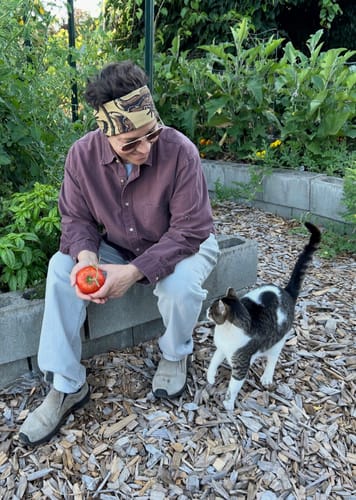 Customer's Flutter Bandana worn as a headband while sitting in a garden with a cat.