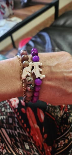 Customer's hand wearing the Shark Week Bracelet with a purple beaded bracelet and a red panda charm bracelet.