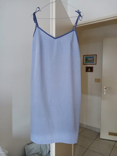Customer's caraco Samia suspendu sur un cintre, présentant un tissu bleu clair à pois fins et des finitions à biais.