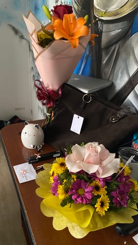 Customer's dark brown Bolso Notebook Trenzado Bohemia bolso sitting on a table with floral arrangements.